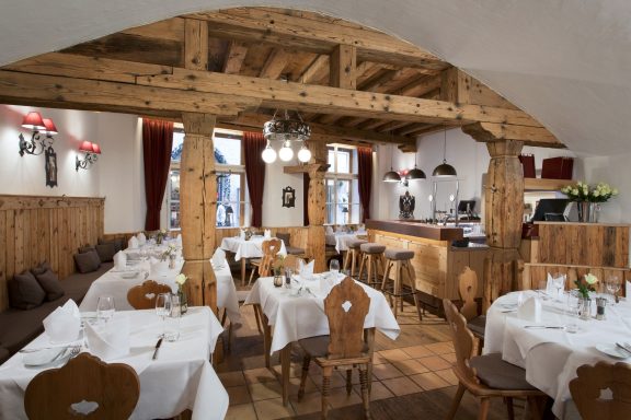 Gemütliches Restaurant mit Holzmöbeln, weißen Tischdecken und sanfter Beleuchtung.
