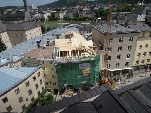 Bauarbeiten an einem Gebäude mit einem Gerüst und einem Kran in einer Stadtlandschaft.