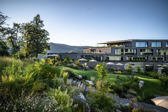 Moderne Architektur umgeben von grüner Landschaft und sanften Hügeln.