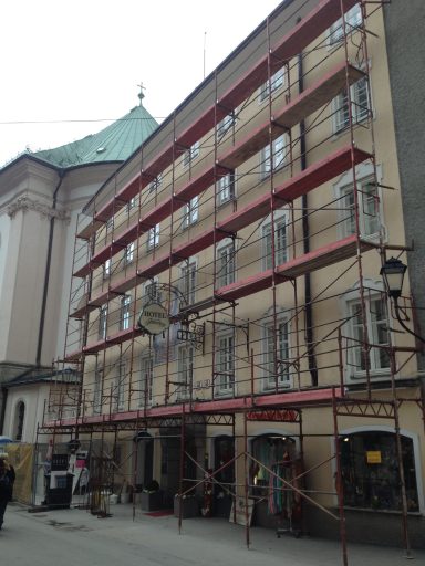 Fassade eines Gebäudes mit Gerüst und Renovierungsarbeiten in einer städtischen Umgebung.